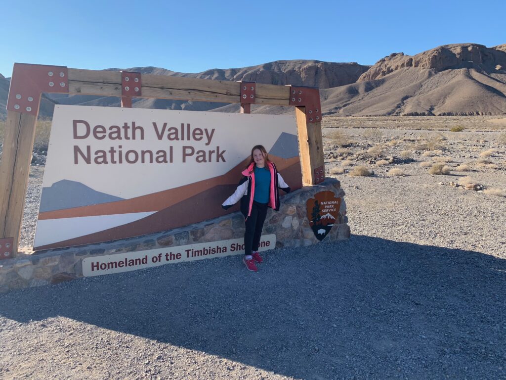 Cameron at the Death valley National Park sign. Standing in the shadow. 