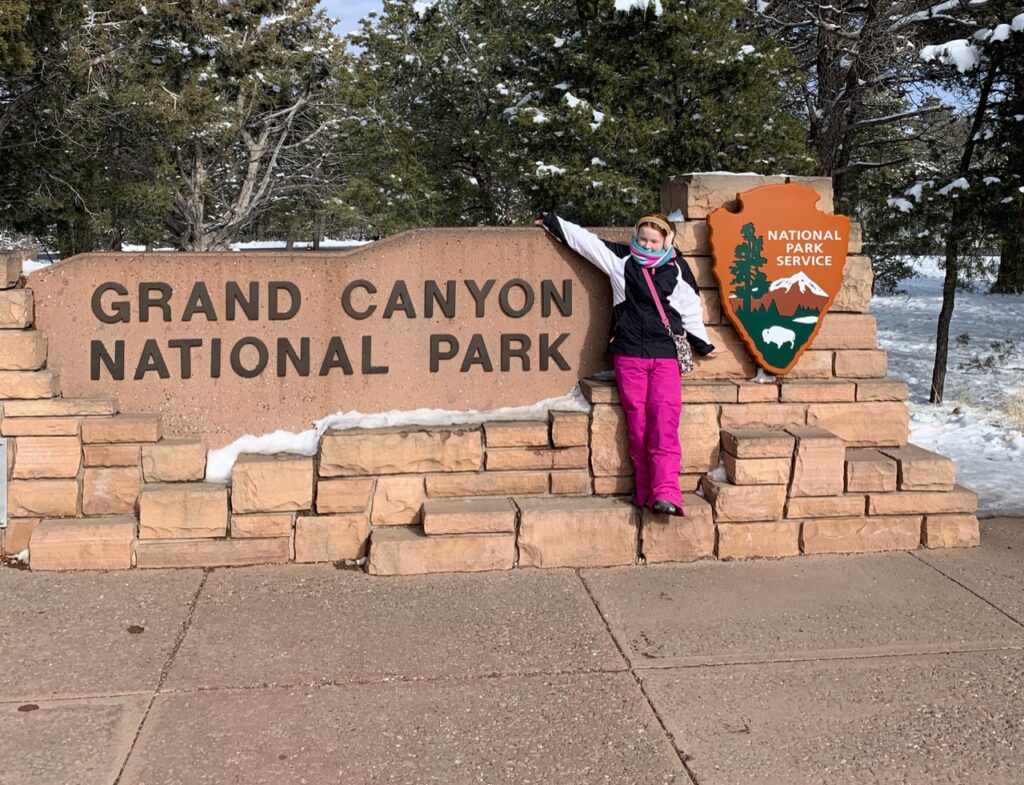 Cameron in front of teh Grand Canyon National Park sign.