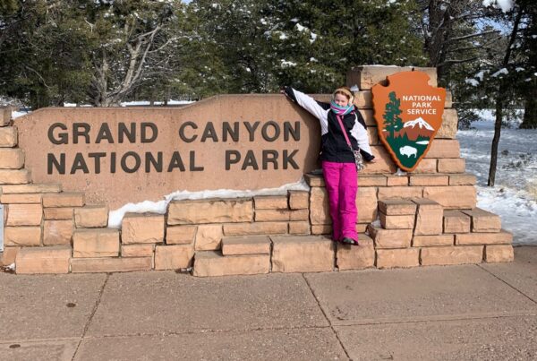 Cameron in front of teh Grand Canyon National Park sign.