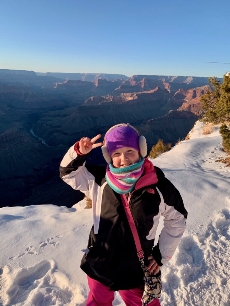 Cameron standing on the Rim Trail of the Grand Canyon in the snow.