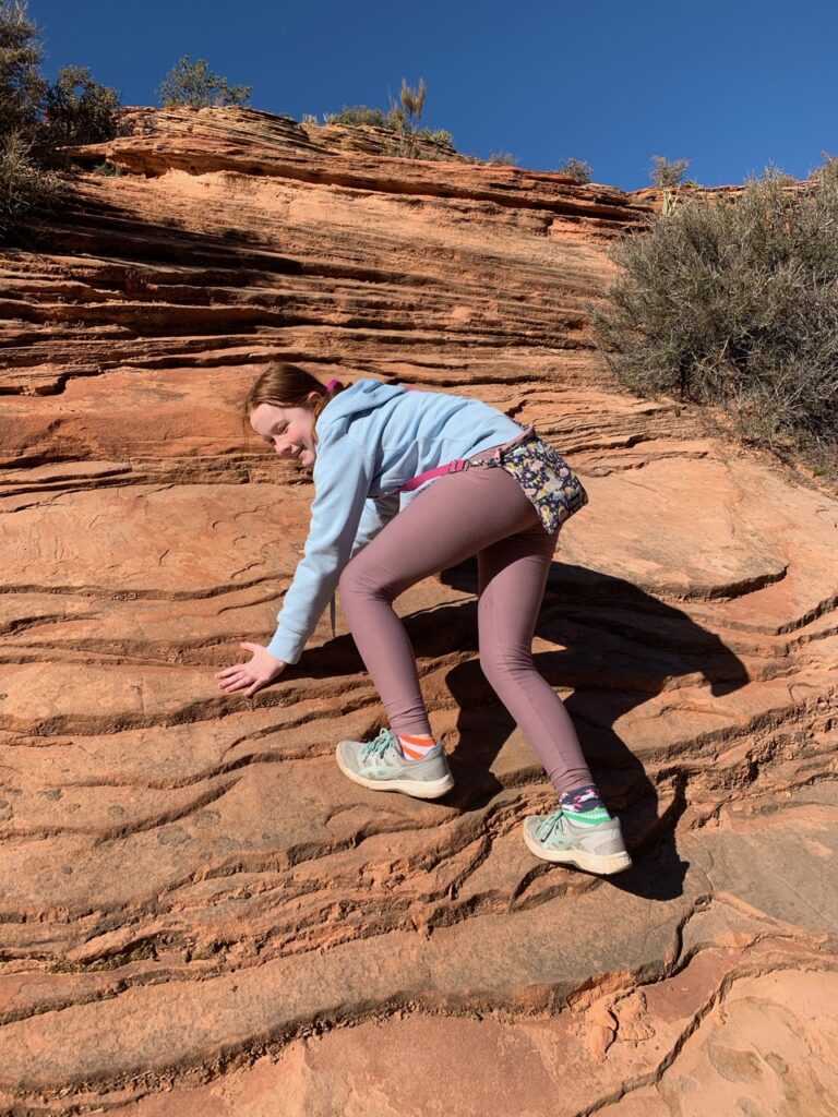 Cameron hiking up steep sandstone rocks in Zion National Park.