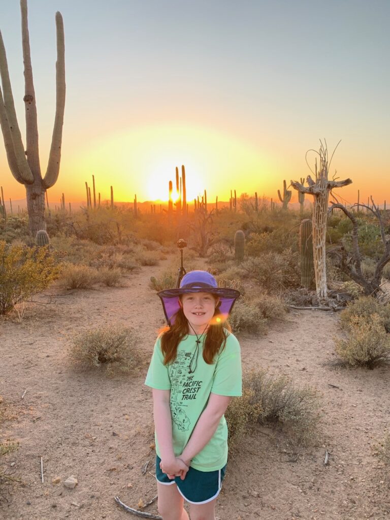 Cameron in the Arizona desert at sunset, with a red sky and a landscape filled with saguaro cactus.