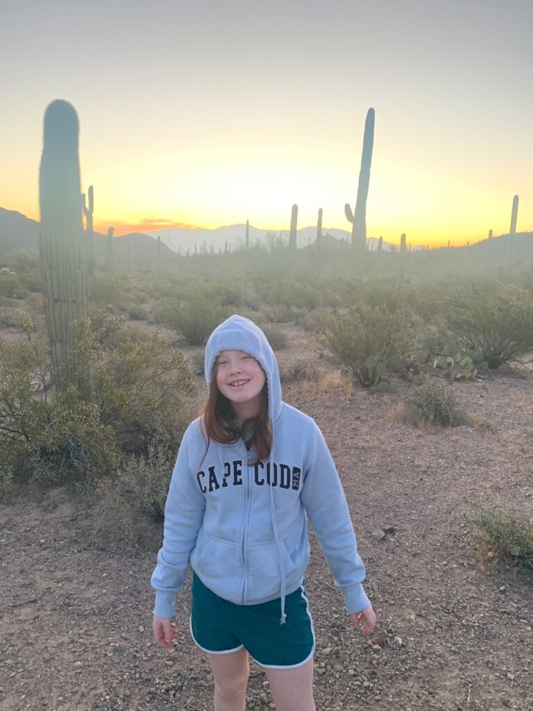 Cameron in a hoodie standing in the desert at sunset in Saguaro National Park.