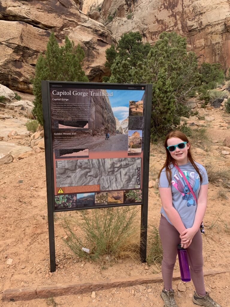 Cameron standing in front of the trail head sign for Capitol Gorge in Capitol Reef National Park.