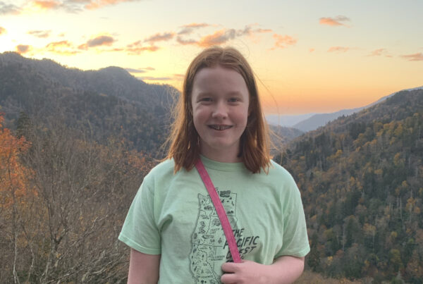 Cameron at sunset with the sky full of reds and yellow clouds and the fall colors in the background of the valley below.