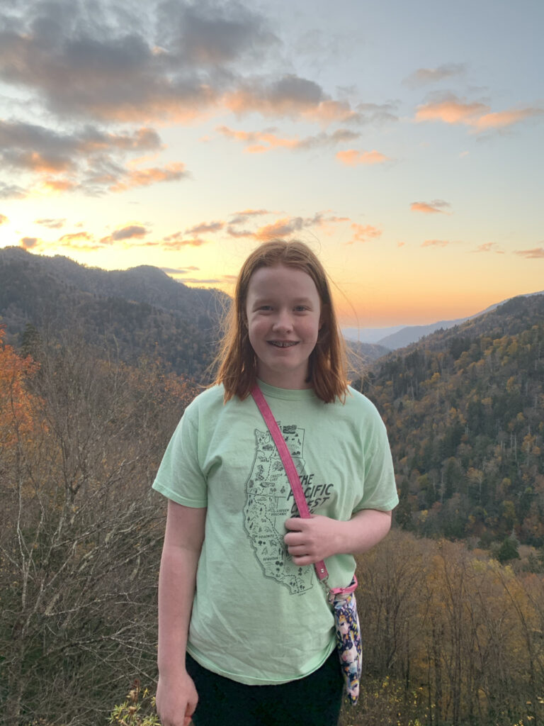 Cameron at sunset with the sky full of reds and yellow clouds and the fall colors in the background of the valley below.