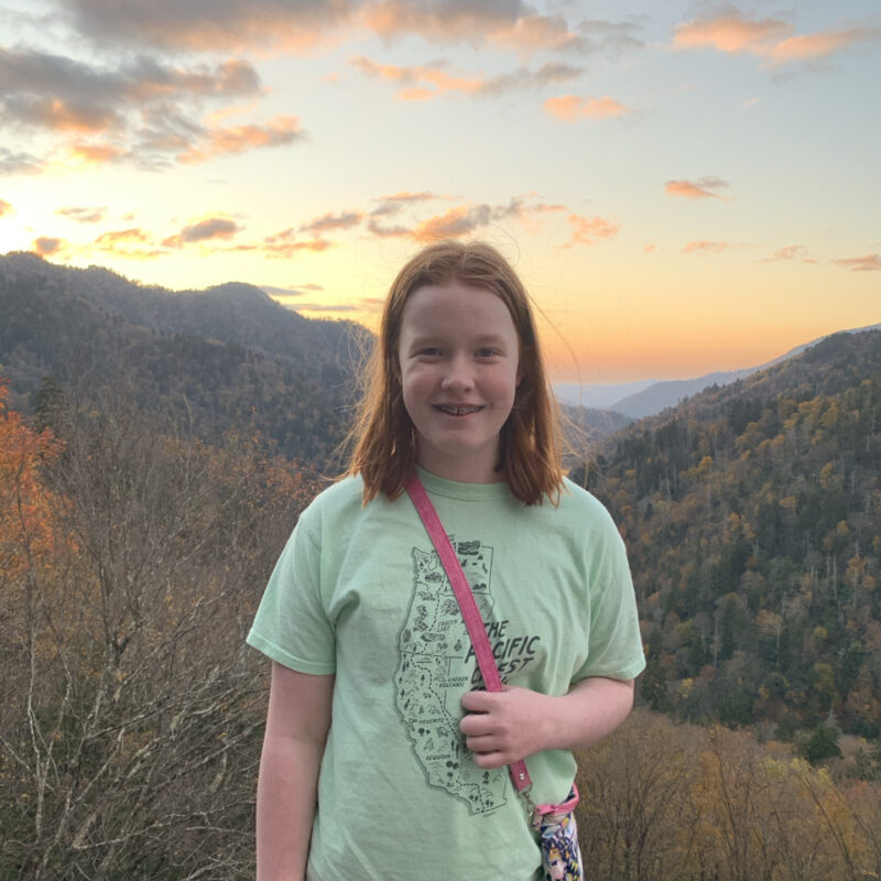 Cameron at sunset with the sky full of reds and yellow clouds and the fall colors in the background of the valley below.