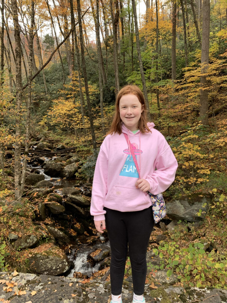 Cameron hiking in the woods by a stream in the Great Smoky Mountain National Park. The leafs are at peak color.