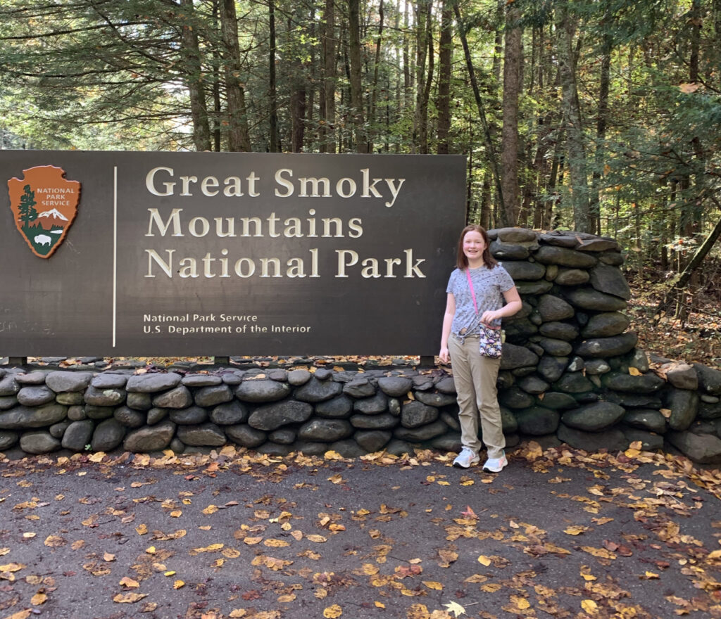 Cameron in front of the Great Smoky Mountains National Park sign at the peak of fall colors.