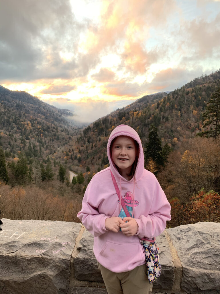 Cameron by the rock wall at Morton Overlook in the Great Smoky Mountains National Park. Taken at the peak of fall and the height of sunset with the clouds lit up in the background just over the valley.