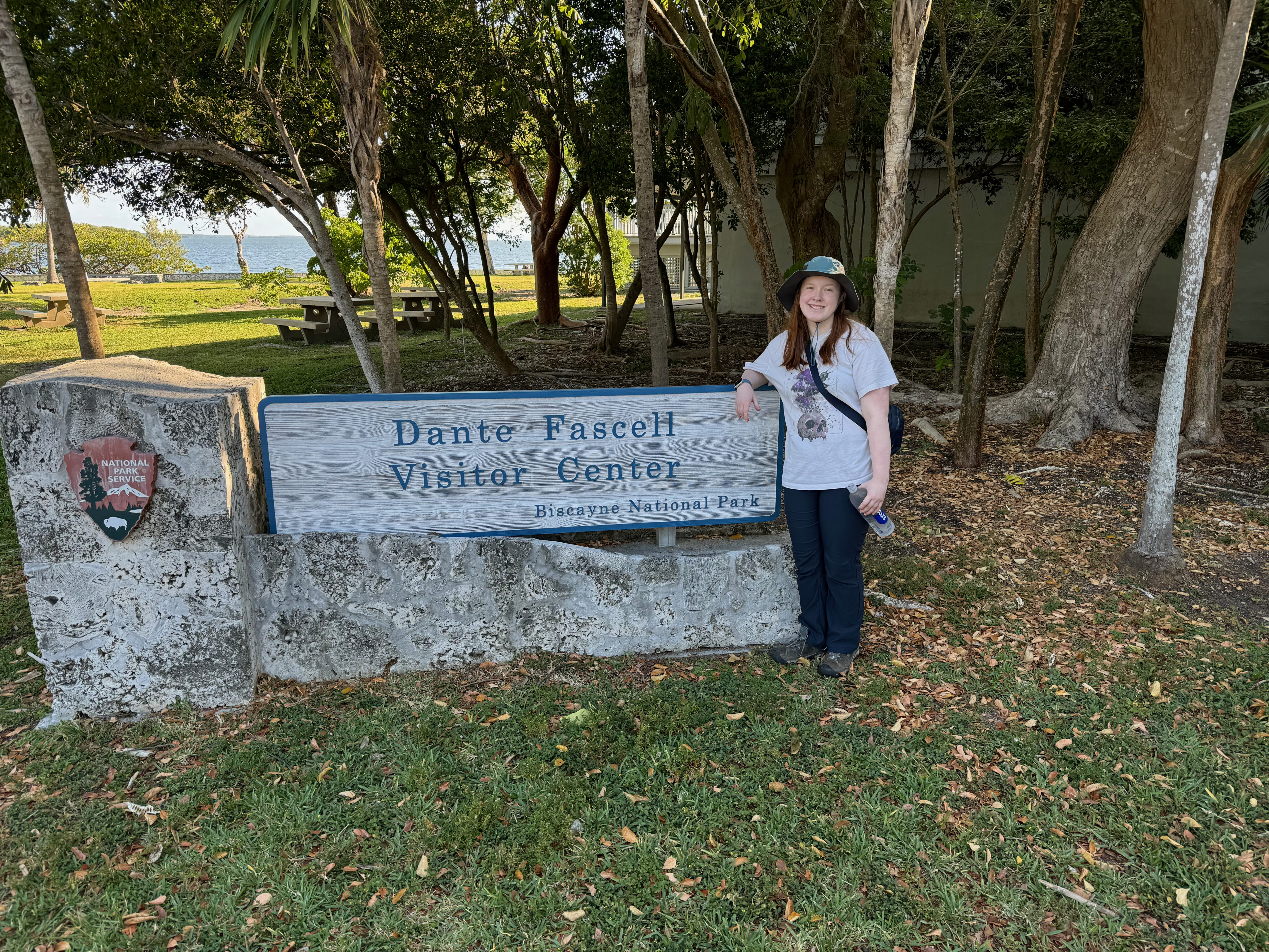 Cameron standing in front of the sign for Dante Fascell Visitors Center in Biscayne National Park. She is wearing a hat and has a huge smile on her face.