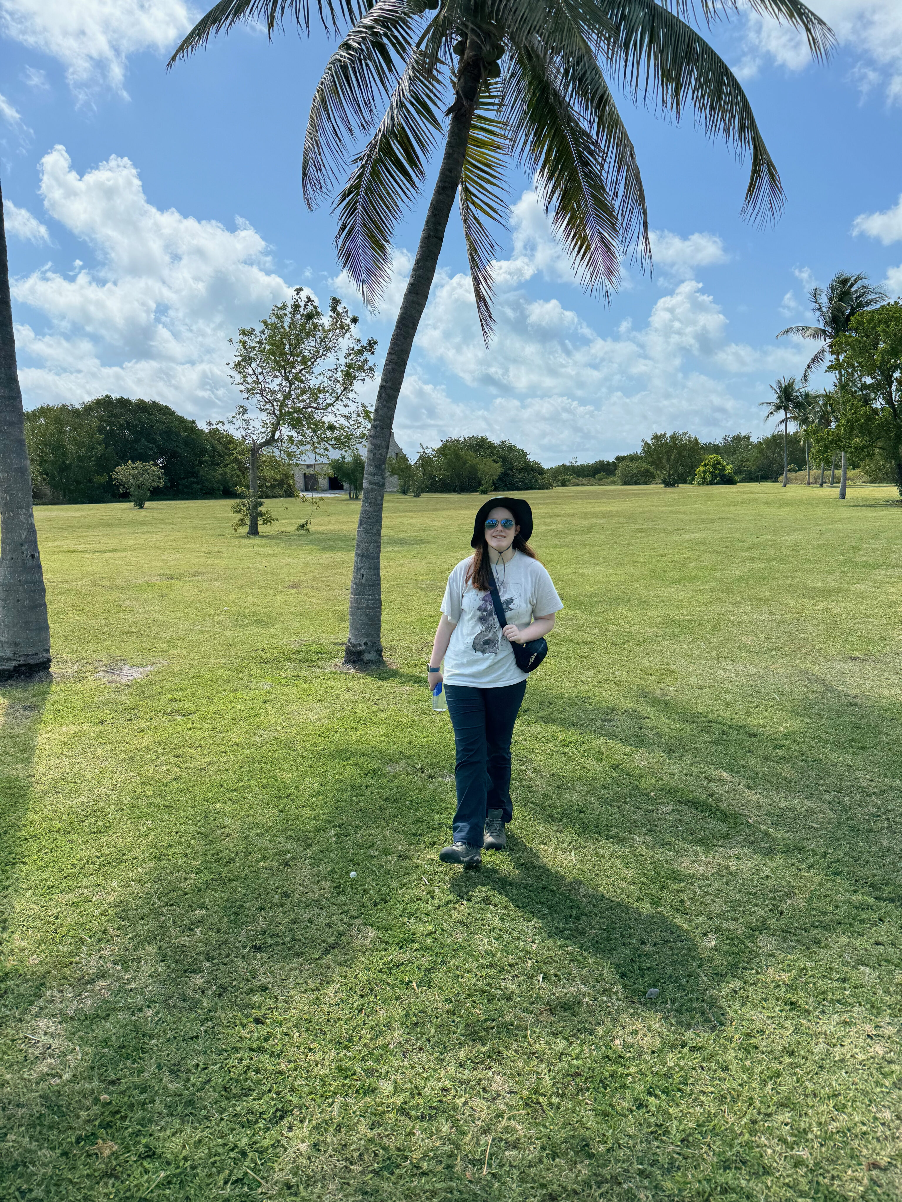 Cameron standing in the shade of a palm tree wearing a hat and sunglasses on Boca Chita Key.