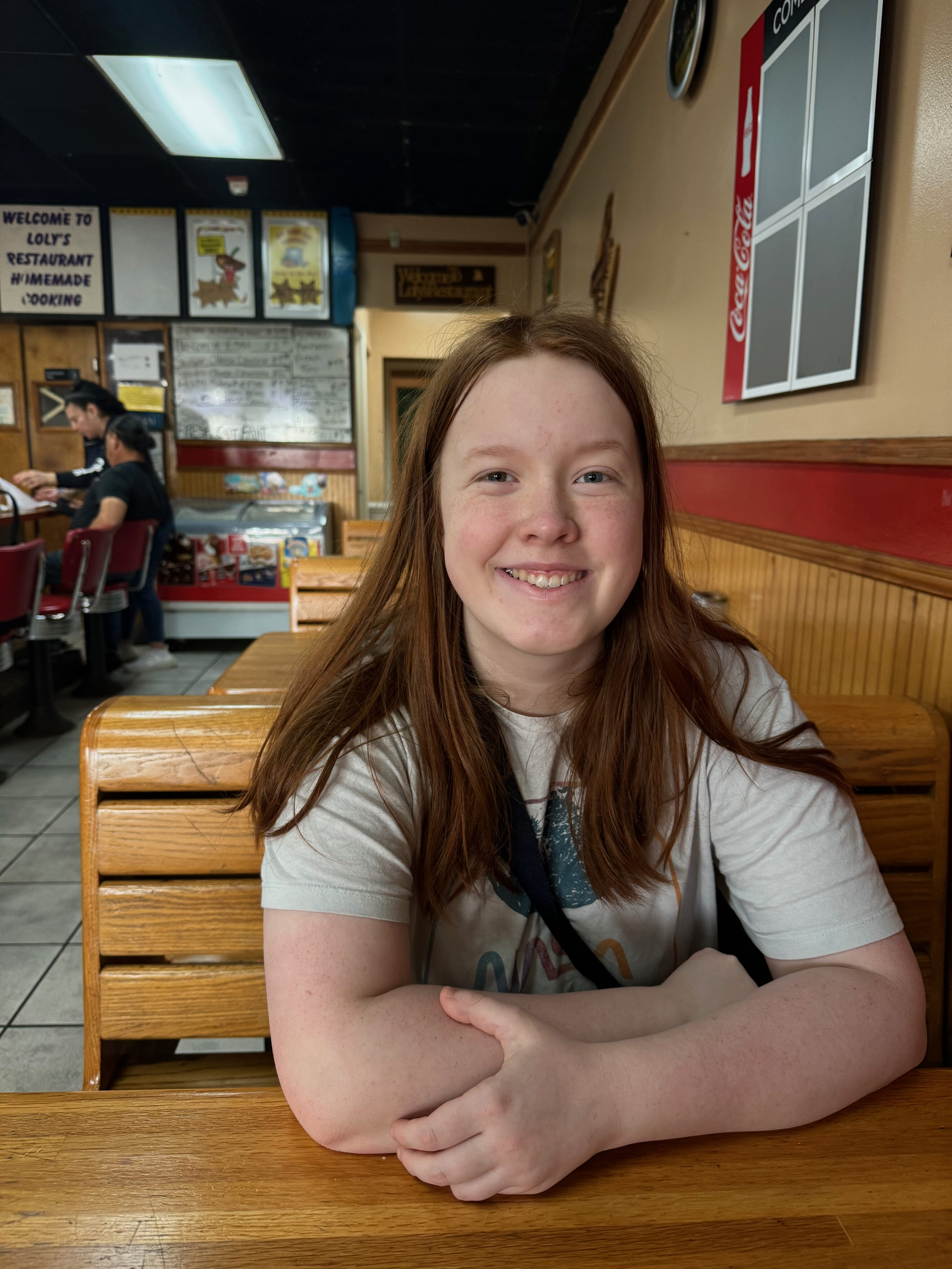 Cameron sitting at a table in Loly's Restaurant waiting for her pancakes. 