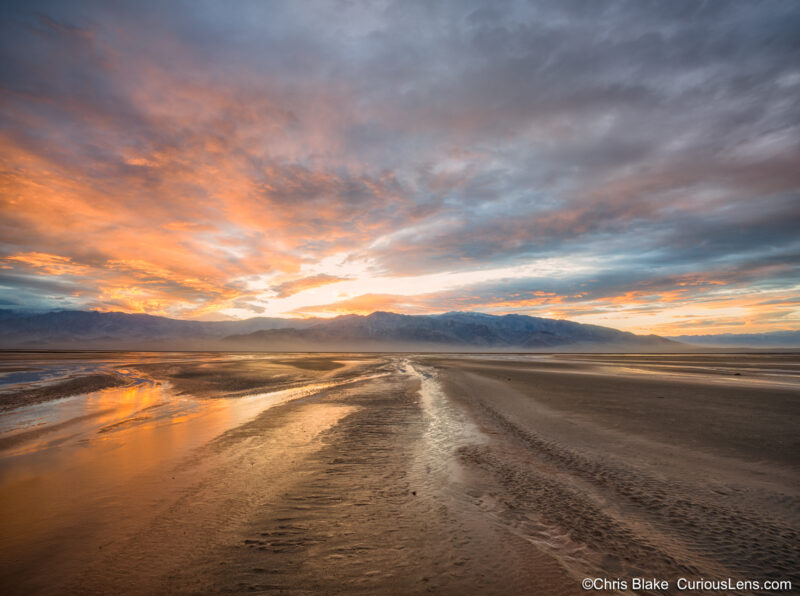 A winters sunset in a wet and rainy Death Valley. The sky is alive with clouds and color and rivers have formed in the desert.