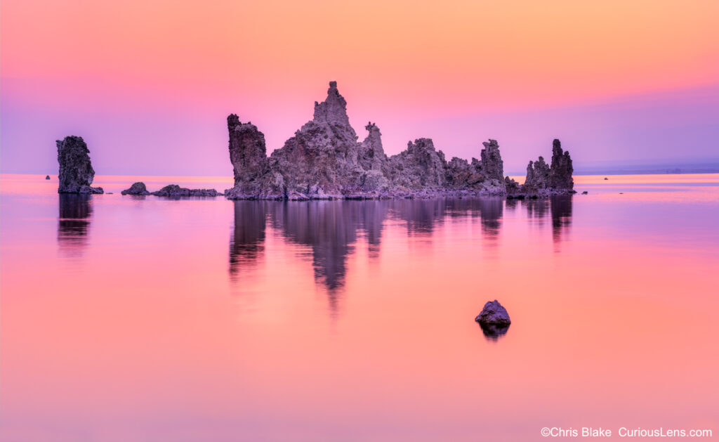 Mono Lake is a saline soda lake in Mono County, California. It features unique Tufa Towers formed by high salt levels. This 400-megapixel image captures the scene just before sunrise, with a calm lake surface reflecting the colorful clouds. The town of Lee Vining and Yosemite's high-country road lie nearby.