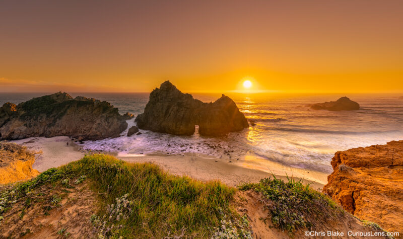 An icon location in Big Sur, this photo taken ontop the bluff looking down at the beach, its purple sand, and the massive sea arch. Taken at sunset as the sun shines through Keyhole Rocks window.