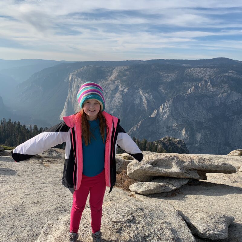 Cameron standing on top of Glacier Point in Yosemite National Park at sunset with a sky full of clouds.