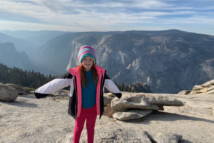 Cameron standing on top of Glacier Point in Yosemite National Park at sunset with a sky full of clouds.