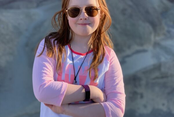 Cameron standing in Death Valley at Artists Palette, with her arms crossed wearing sunglasses.