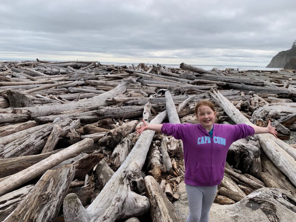 Cameron standing on logs on the shores of Second Beach near La Push in Olympic National Park.