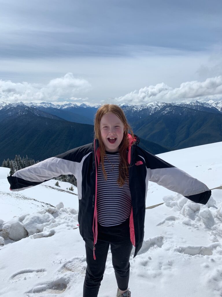 Cameron standing onto of Mount Olympus in the snow wearing a winter jacket.