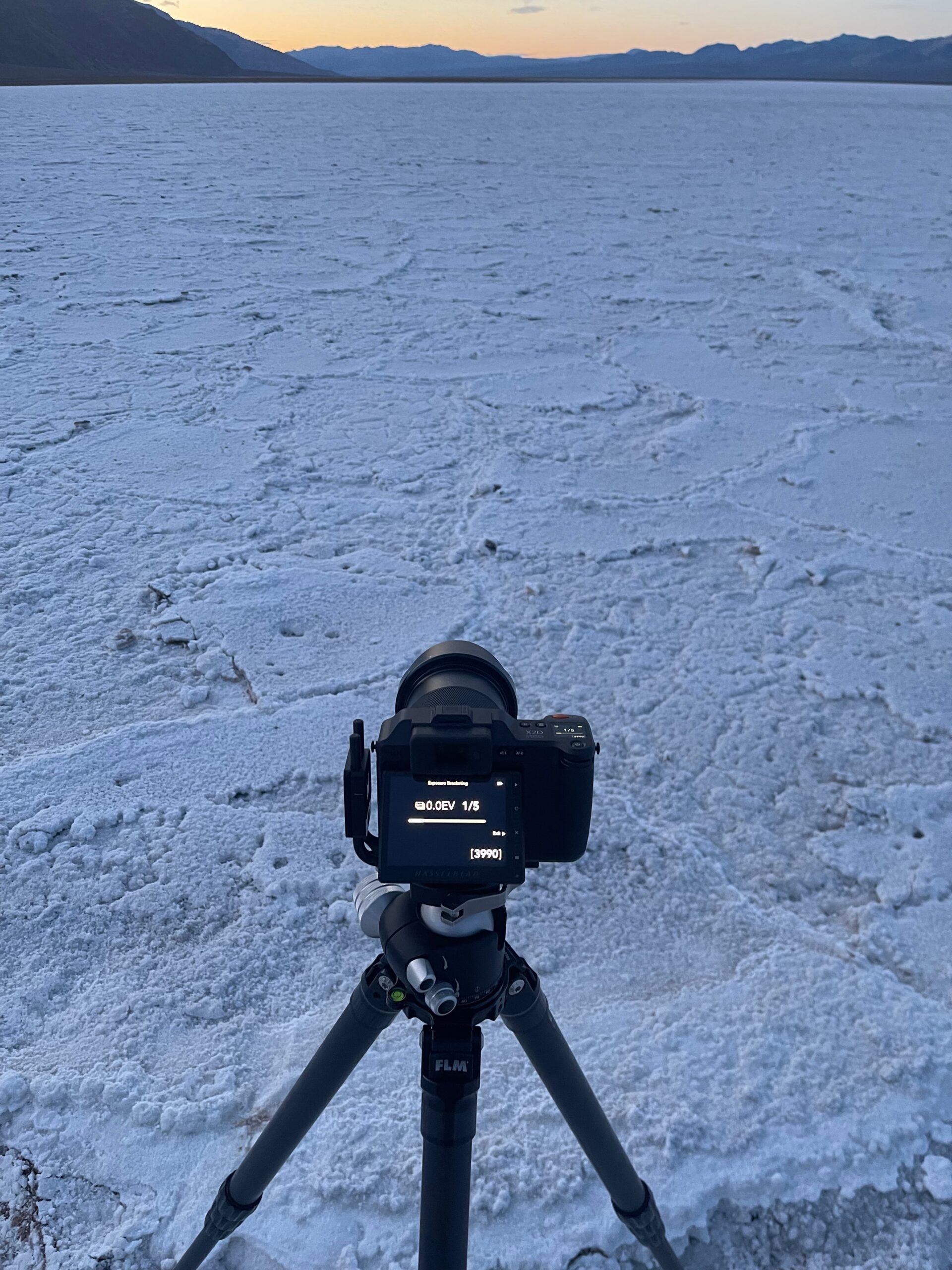 My camera, Hasselblad X2D on a tripod on the salt flats at dawn in Death Valley.