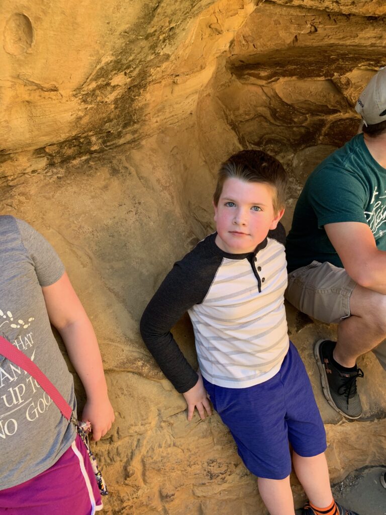 Collin standing on the rocks and shade on the Cliff Palace tour in Mesa Verde National Park.