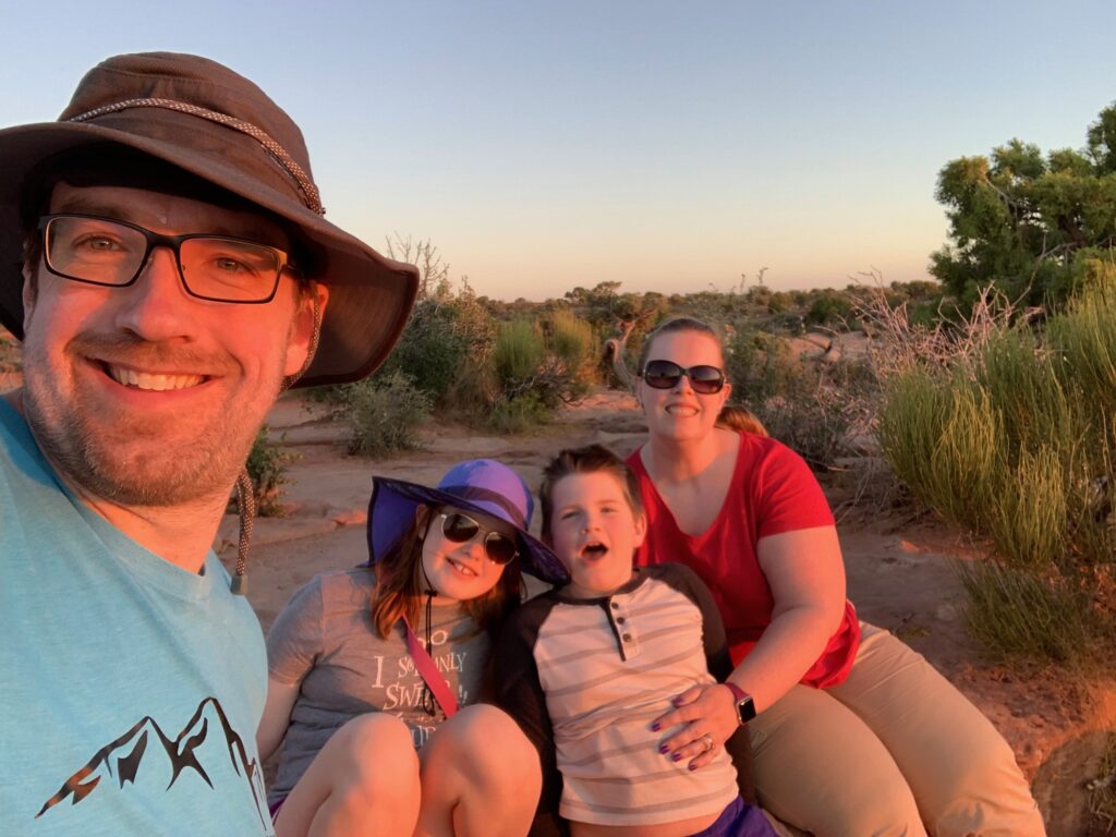 The entire family sitting for a photo at Sunset at Dead Horse Point state park in Utah.