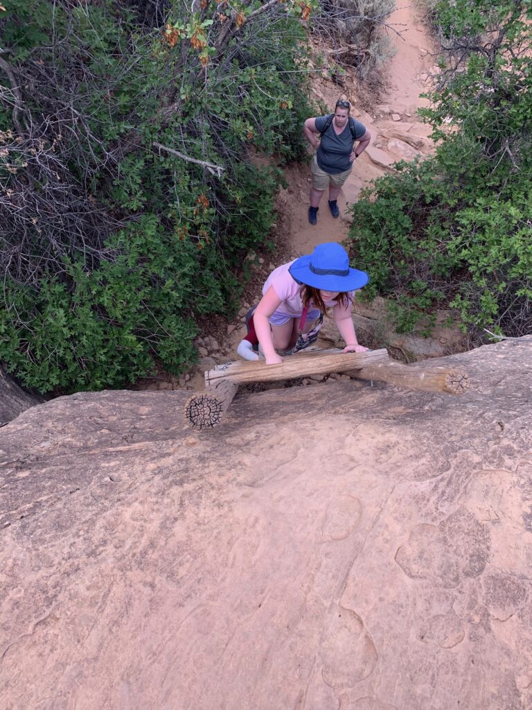 Cameron climbing a ladder on the Cave Springs trail in the Needles District of Canyonlands National Park with mom watching from the trail.