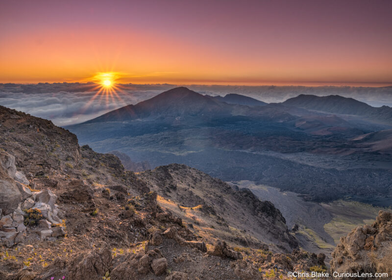 Leleiwi Overlook in Haleakalā National Park, offering solitude and stunning views of East Maui Volcano. Captures the moment when the sun rises over the clouds, casting light on the volcano rim while the crater remains in shadow.