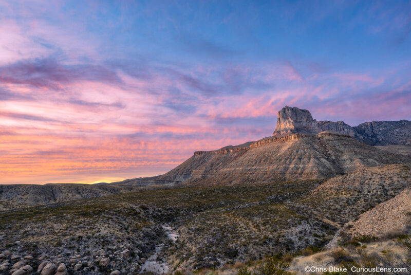 View of El Capitan at Guadalupe Mountains National Park in Texas. This shot captures the peak illuminated by a brilliant red sunset. Guadalupe Mountains National Park is known for its high mountains, including Guadalupe Peak, the tallest point in Texas at 8,751 feet, as well as the iconic Salt Basin Dunes and expansive grasslands. The stormy weather provided a dramatic backdrop for the photo.