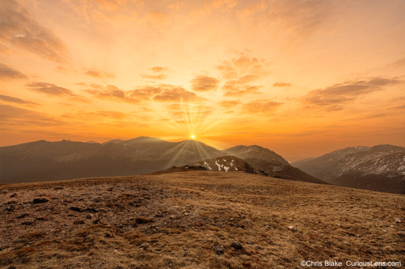 Sunrise at Alpine Ridge in Rocky Mountain National Park with yellow clouds, high alpine tundra, illuminated mountains, and fall colors.