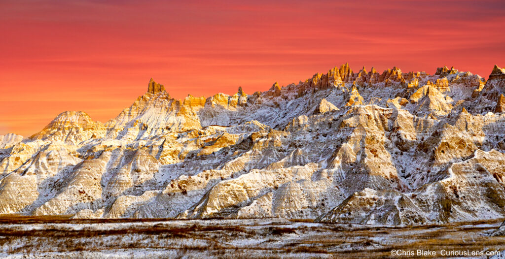 Sunrise in Badlands National Park with fresh snow, red sky, warm light on the valley, and cold early October weather.