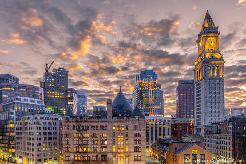 Boston Financial District with Custom House at sunset, soft yellow sky, State Street Bank building, and empty streets.