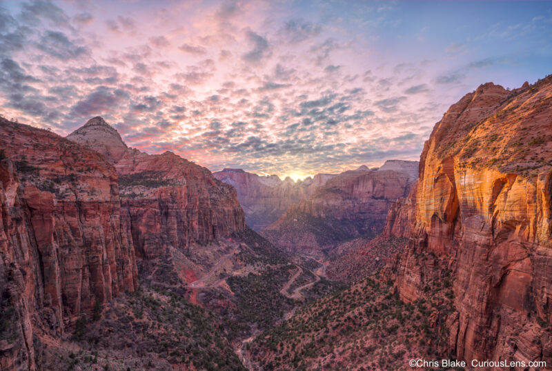 Sunset at Canyon Overlook Point in Zion National Park with Route 9 switchbacks, East Temple, Pine Creek Stream, and dramatic clouds and light.