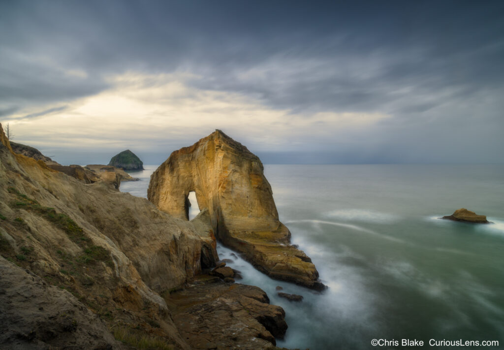 Pacific Northwest cliffs at sunset with sea stacks, rock formations, crashing waves, approaching rainstorm, and dramatic light to dark transition."