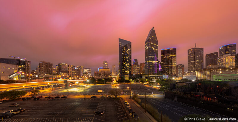 Dallas skyline during stormy sunset with iconic buildings, dramatic clouds, city lights, and vibrant sky colors.