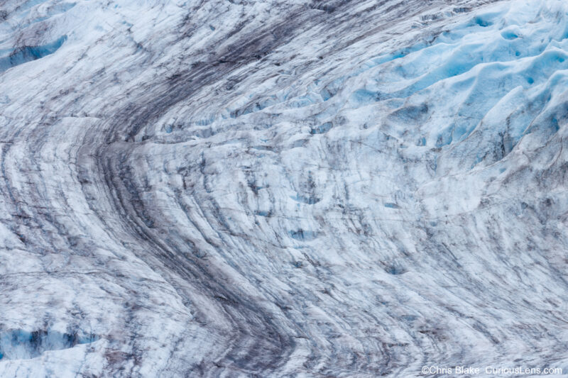 Exit Glacier in Harding Icefield with dark snow leading lines, blue glacial ice, and soft late afternoon light, highlighting its rapid retreat due to climate change.