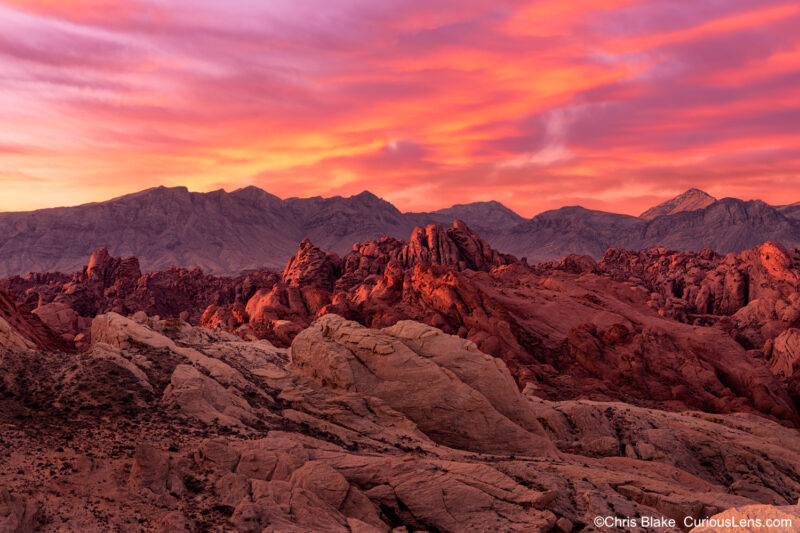 Sunrise at Fire Canyon in Valley of Fire State Park with three layers of rocks, red and yellow clouds, and first light of day.