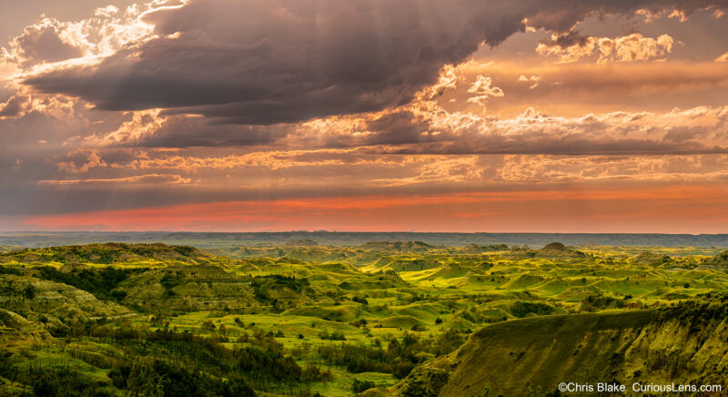 Prairies and grasslands of Theodore Roosevelt National Park with sun rays and red horizon during western thunderstorms.