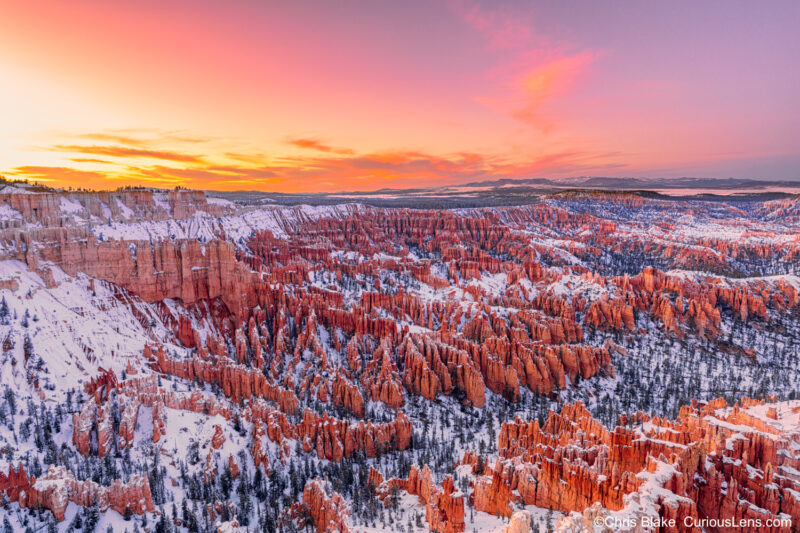 Winter night at Bryce Canyon from Bryce Point with stunning sky, clouds, snow-covered landscape, and red rock formations.