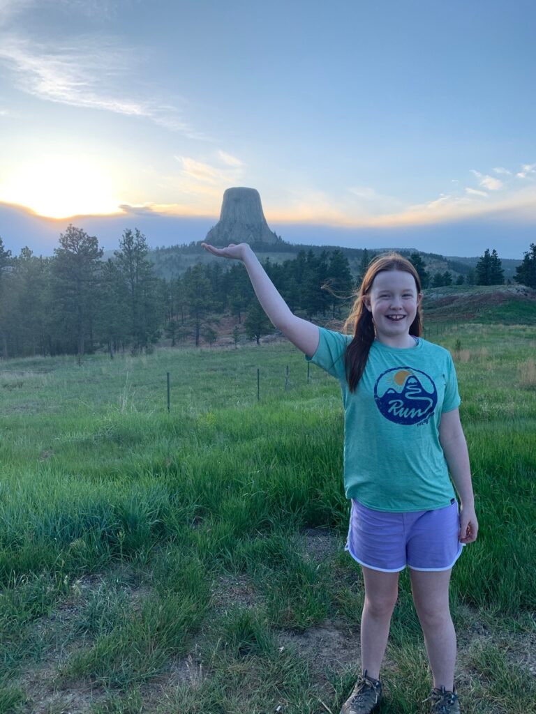 Cameron standing in a field near the Devils Tower at sunset.