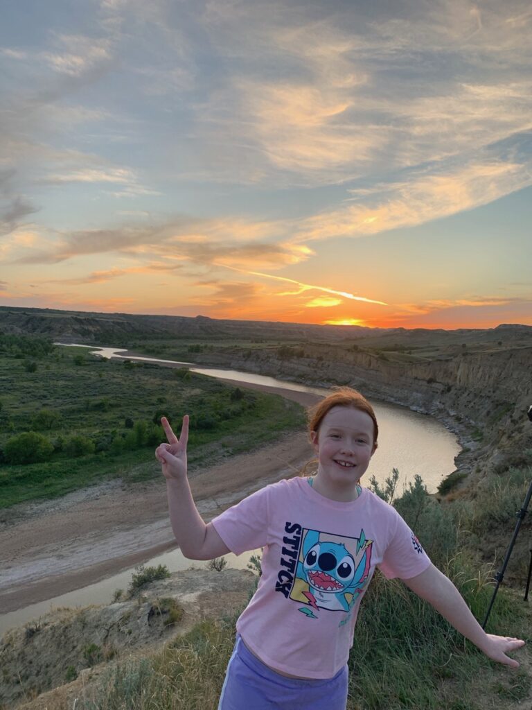 Cameron standing at sunset with a bright red sky at the Wind Canyon Trail, looking down on the Little Missouri River.