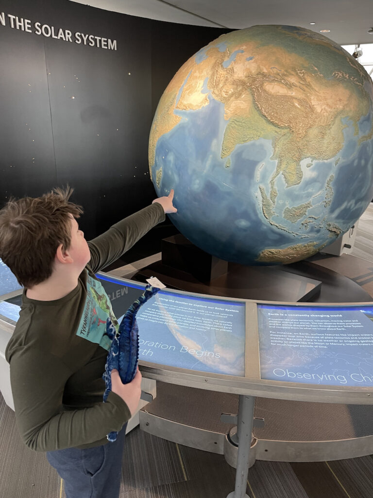 Collin pointing at a globe inside the Adler Planetarium.