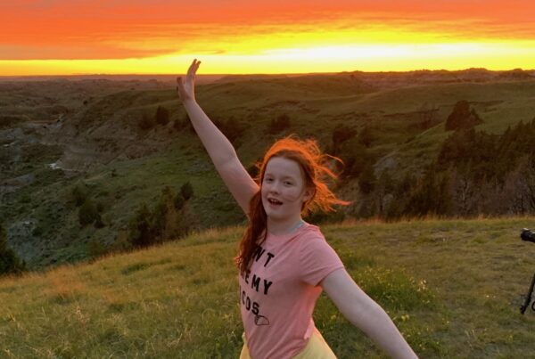 Cameron posing during a amazing red sunset, her hair glowing red with the last light of day at the Boicourt Overlooking, looking down on the Little Missouri Badlands.