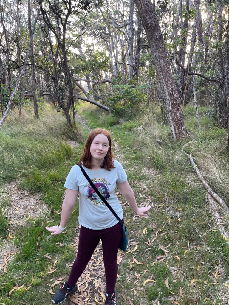 Cameron stopping the hike to pose for a photo on the Crater Rim Trail in Volcanos National Park. A slim trial is carved through dense Hawaiian forest.