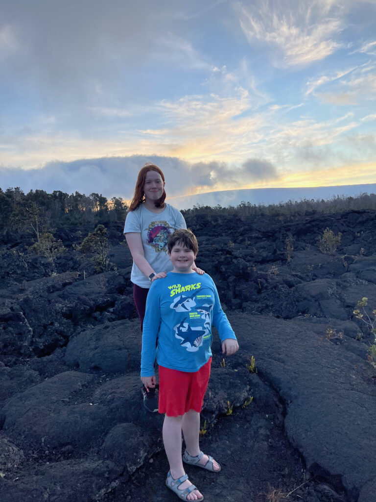 Cameron and Collin at sunset on the Devastation Trial in Volcanos National park. Both standing on hardened lava with a stunning sunset sky.