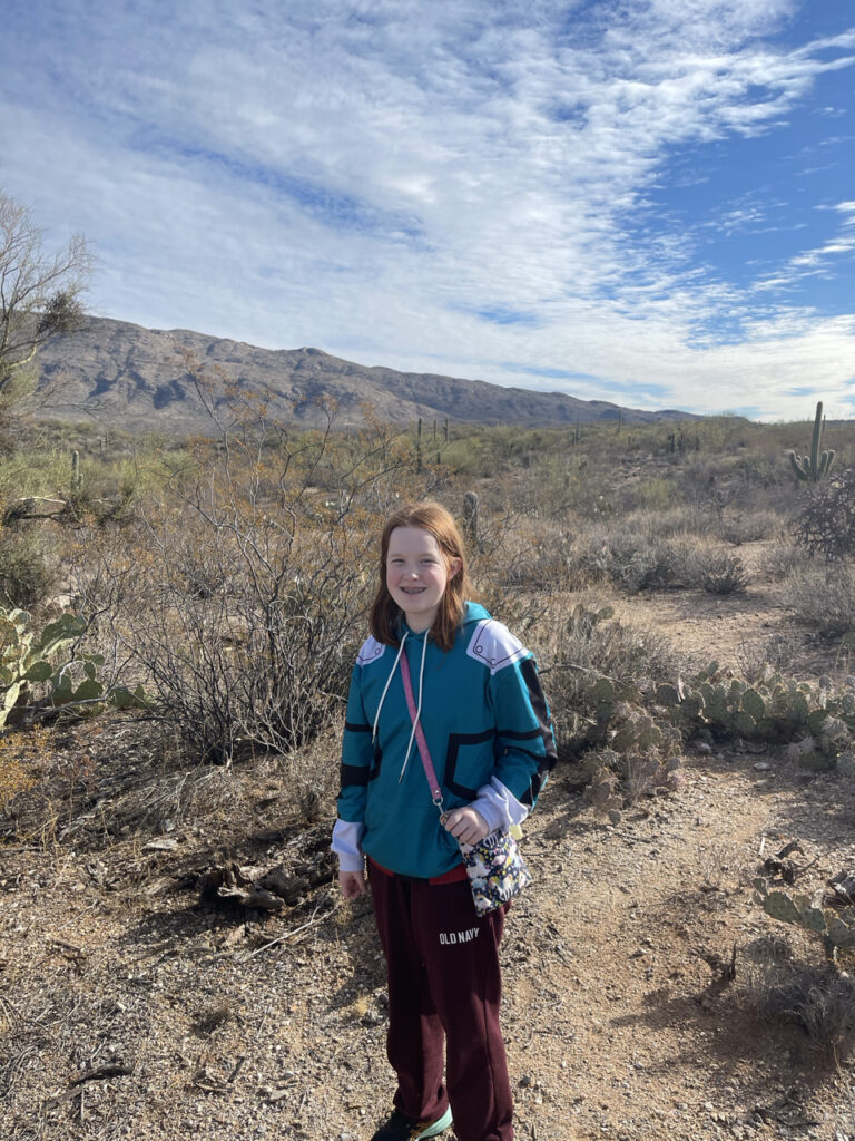 Cami hiking in the desert of Saguaro National Park on the east side, with cactus all around. 