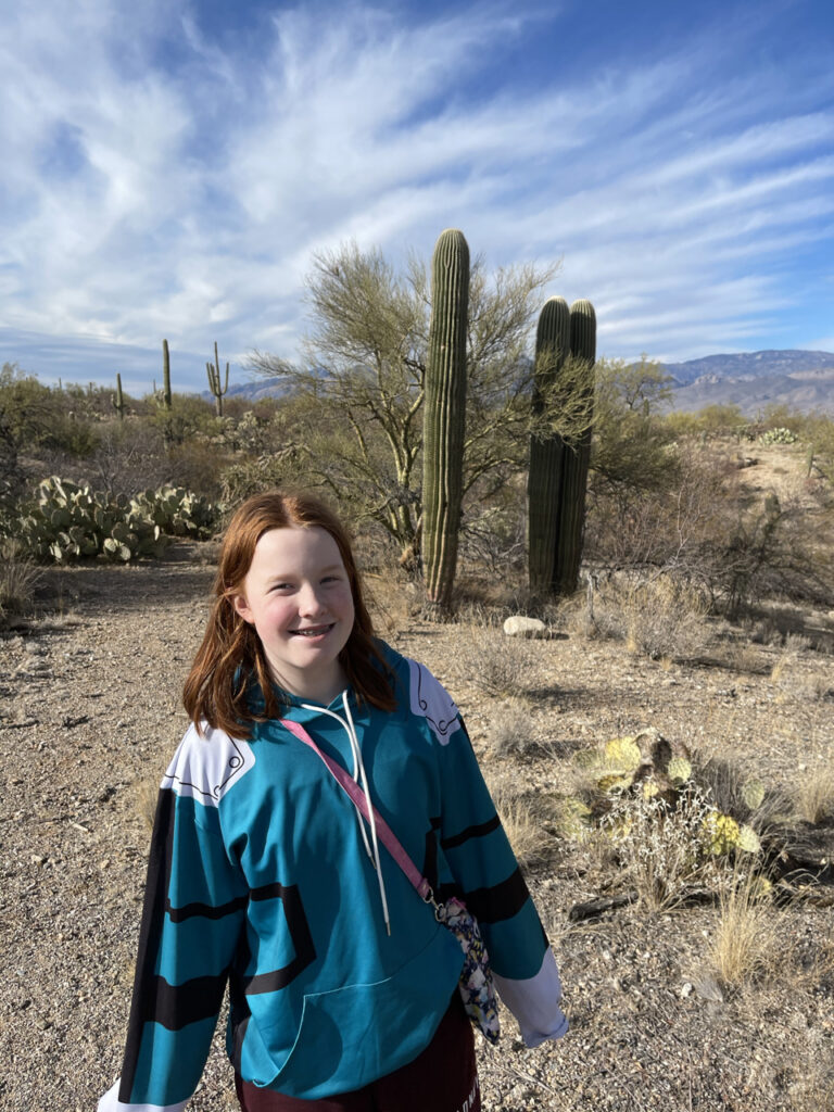 Cami standing in the desert with saguaros behind her in the Rincon Mountain District of Saguaro National Park.