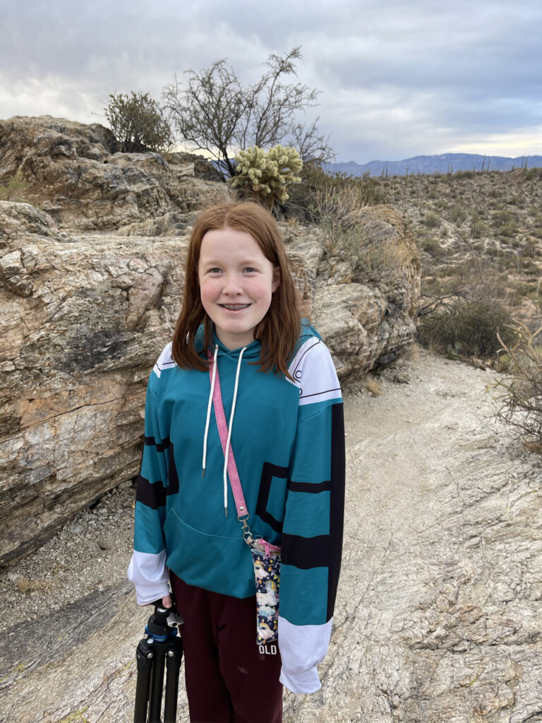 Cameron posing for a photo at the top of Javelina Rocks on the east side of Saguaro National Park, storm clouds where overhead and a full desert full of cactus in the backdrop. 